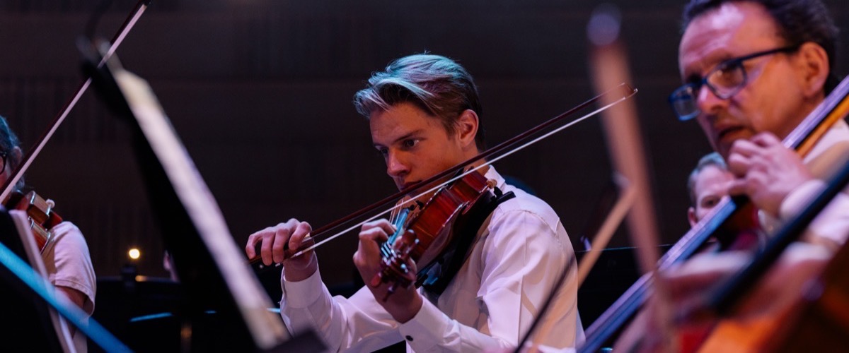 Graph depicts a group of musicians playing string instruments, likely violins, in an orchestra setting.