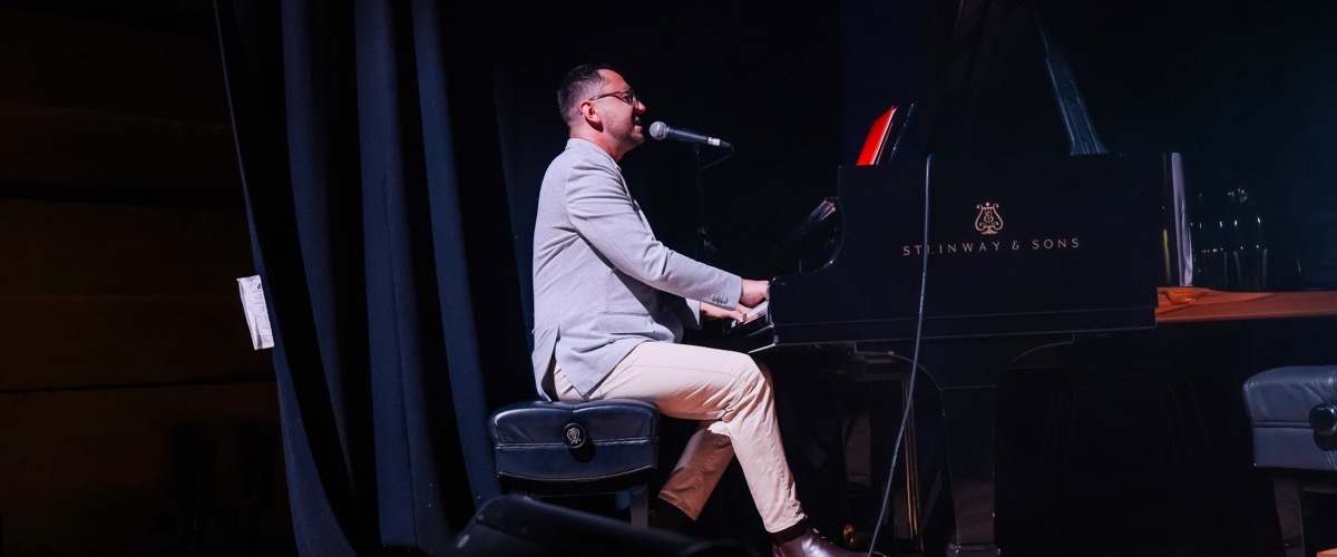 A man playing a piano with a microphone positioned in front of him.