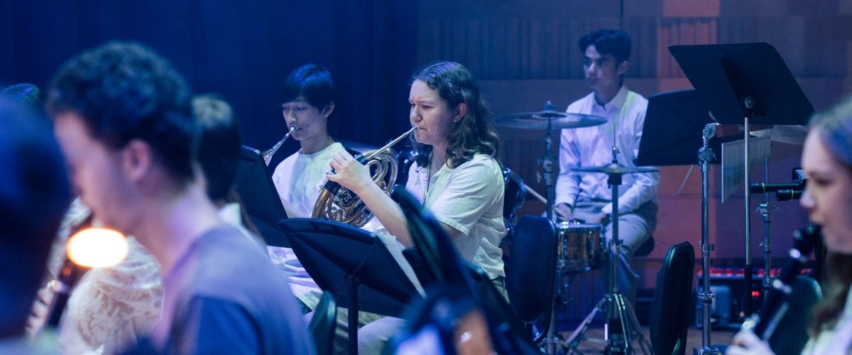 A group of people playing musical instruments, with some wearing white shirts.