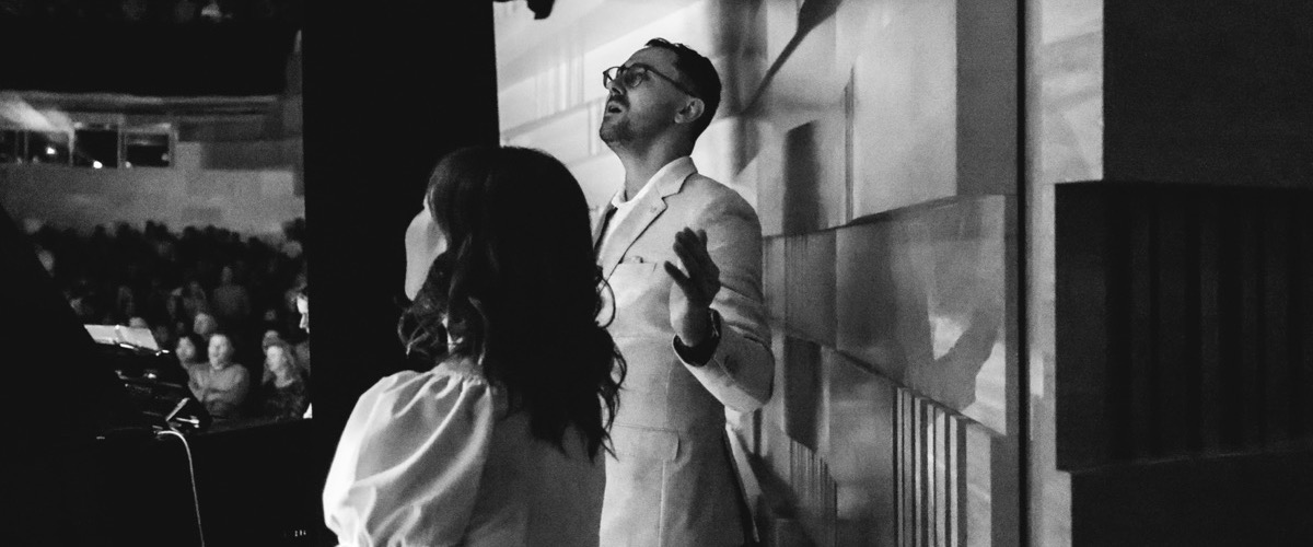 The photograph depicts a man and woman in a dimly lit room, likely at a concert or performance.