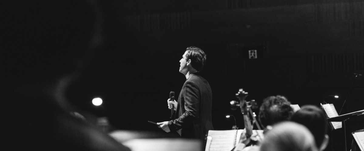 A man standing in front of a group of people with musical instruments.