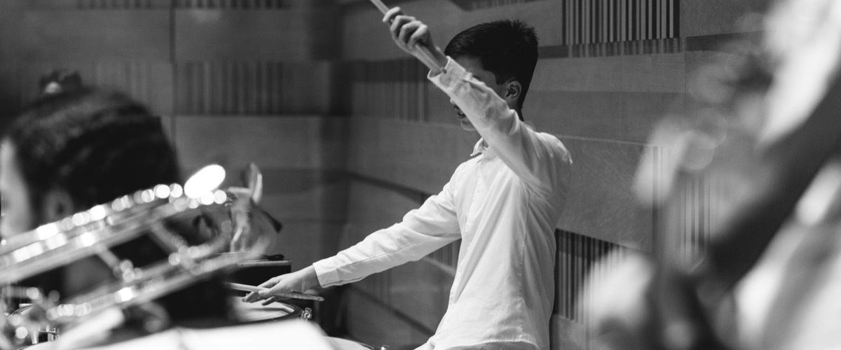A black-and-white photograph of a man playing a musical instrument, likely a trumpet.