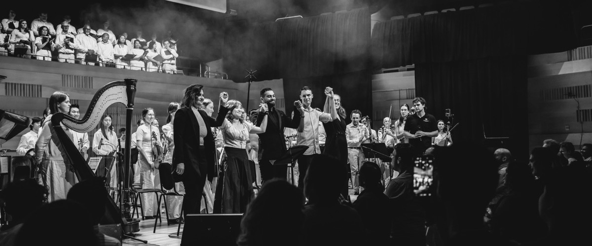 This black-and-white photograph depicts a group of musicians taking a bow on stage after a performance.