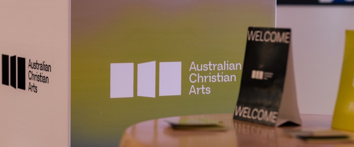 A welcome sign on a table, accompanied by a green and white logo in the background.