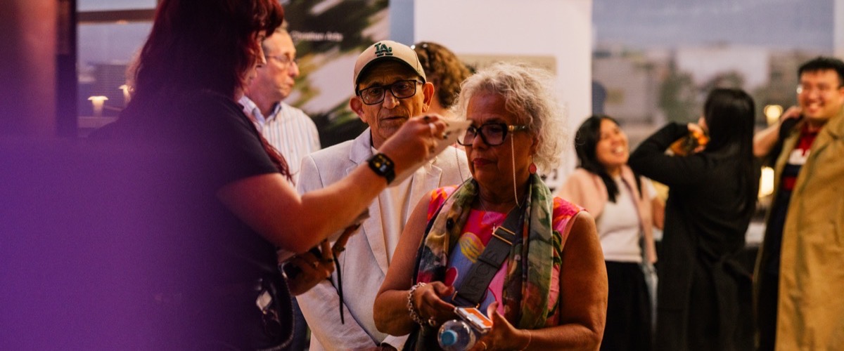 A group of people gathered at an event, with a woman in the foreground holding a camera.