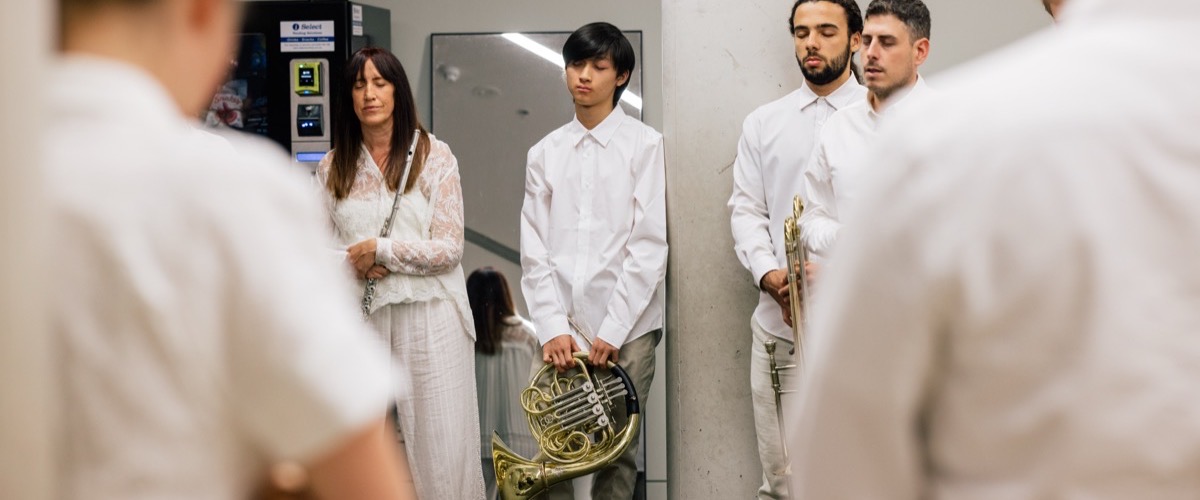 Graph depicts a group of musicians in white attire, with a woman and a man holding a French horn.