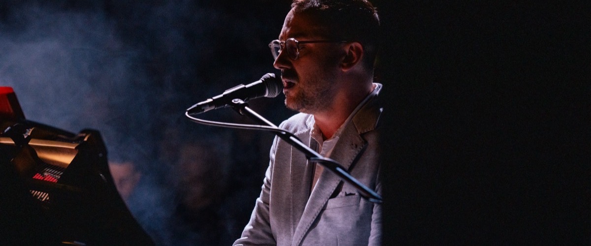 Graph depicts a man singing into a microphone while seated at a piano.